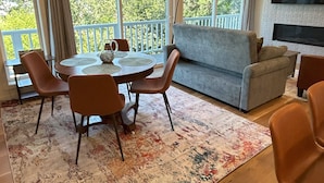 Ein modernes Wohnzimmer mit einem runden Esstisch, zwei Sofas und einem an der Wand befestigten Fernseher.