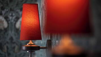 A wall-mounted lamp with a red shade.