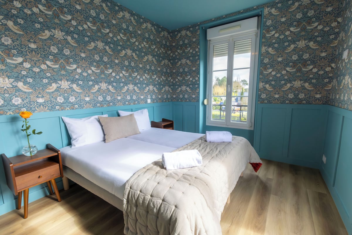 Une chambre à coucher avec un lit, une table de chevet, une fenêtre et une porte.