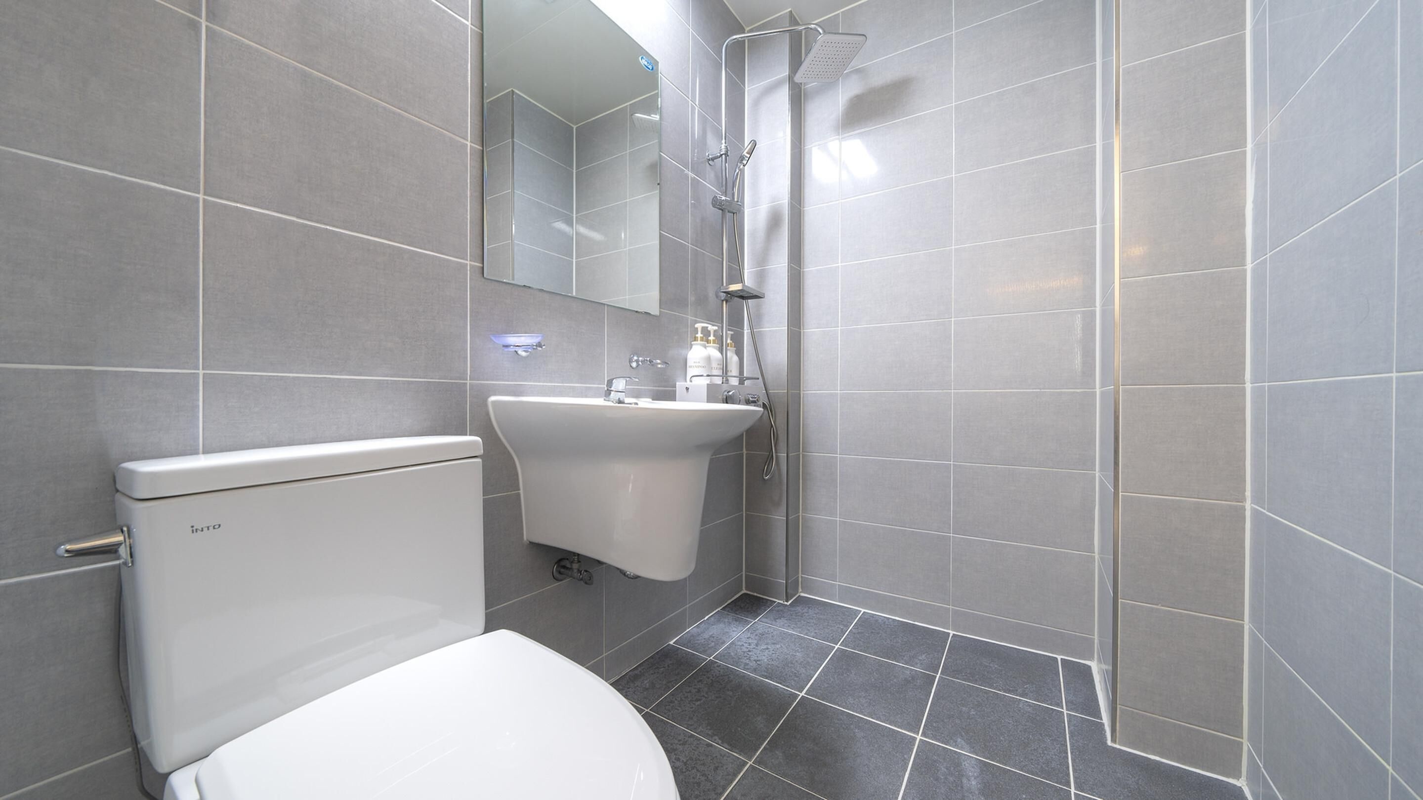 Un baño moderno con inodoro, lavamanos y ducha.