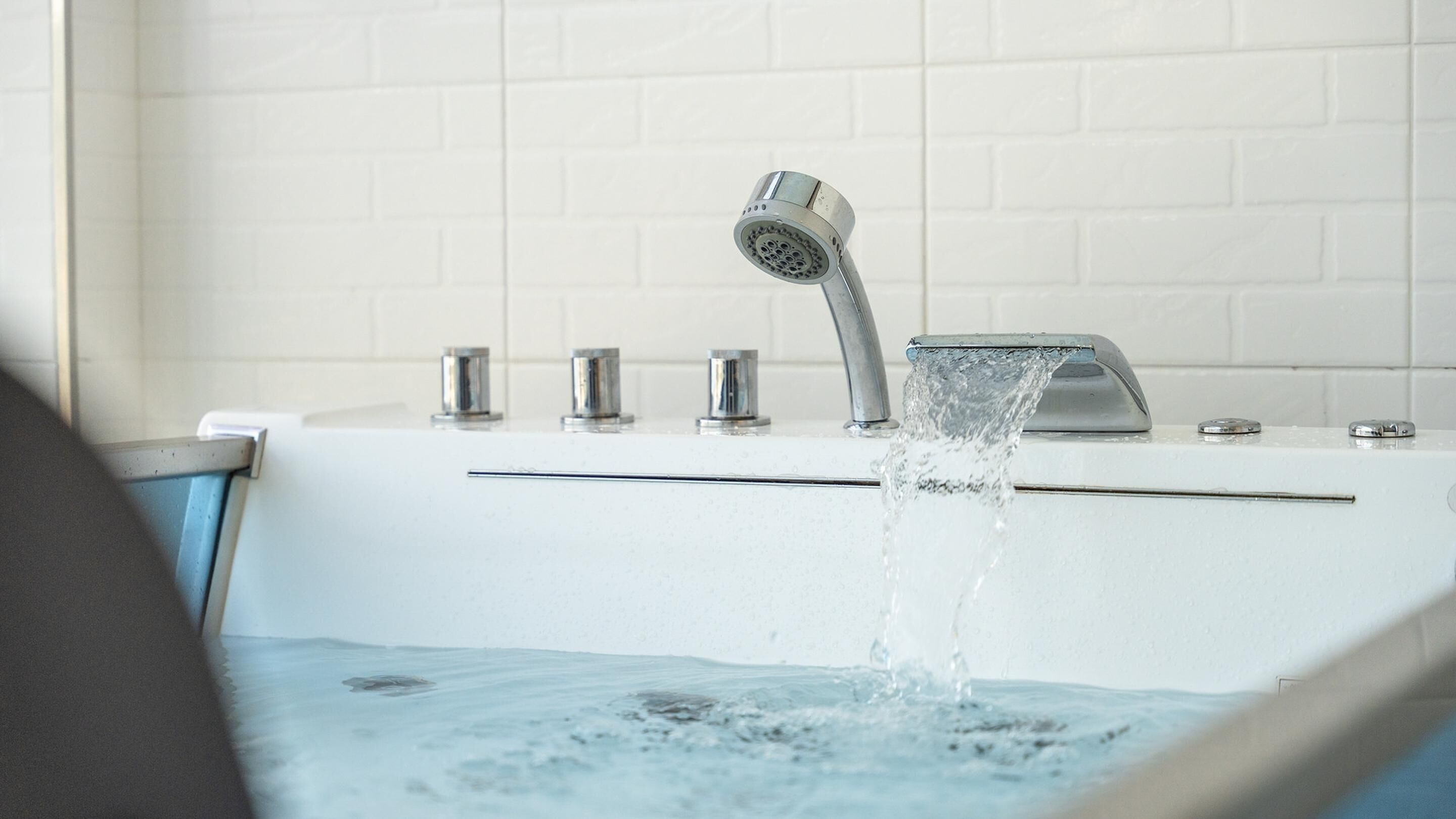 A bathroom with a bathtub, a showerhead, and a faucet.