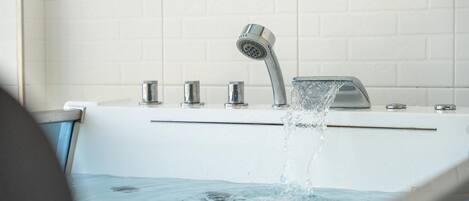 A bathroom with a bathtub, a showerhead, and a faucet.