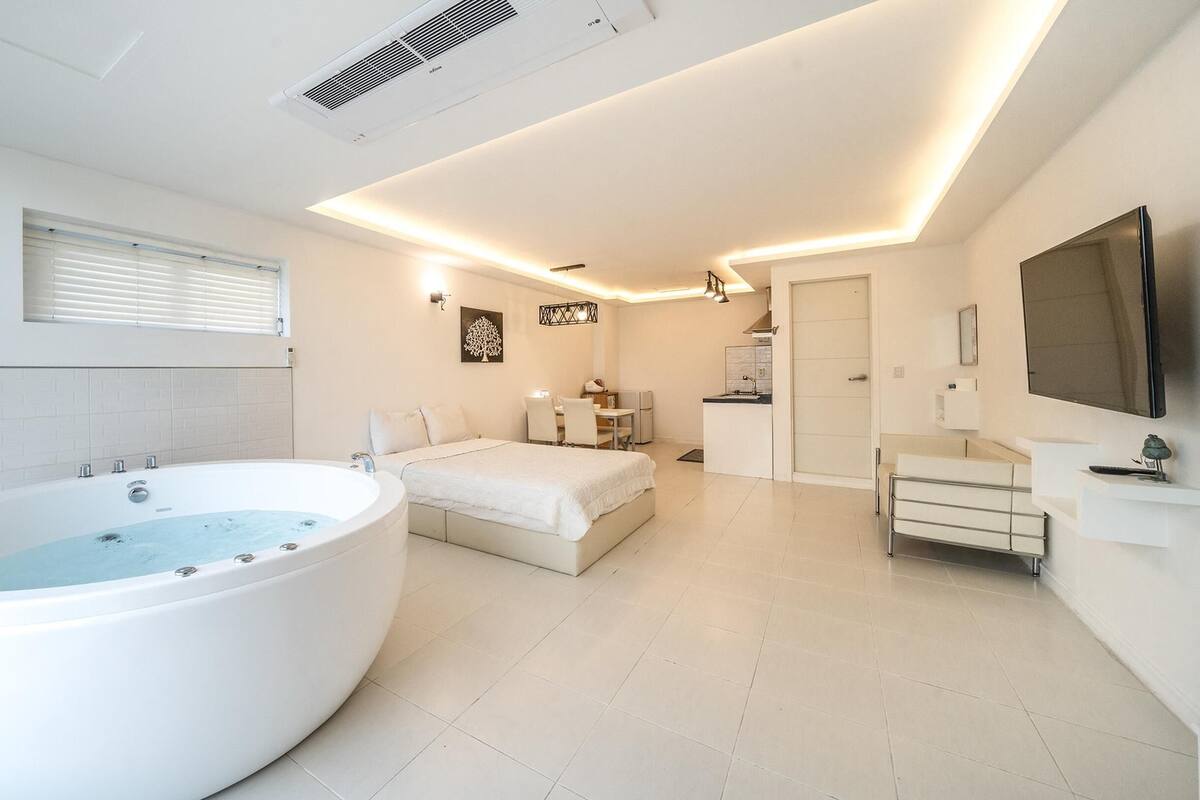 A modern bathroom with a large freestanding bathtub, a separate shower area, and a small kitchenette.