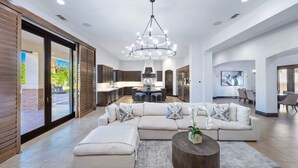 A modern living room with a sectional sofa, a coffee table, and a chandelier.