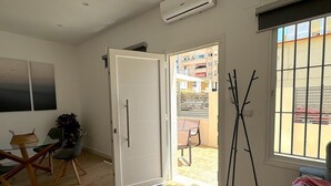 A room with a wooden floor, a dining table with chairs, a potted plant, and a large window with bars. - SibsSanlucar Guadalquivir (Sanlúcar de Barrameda)