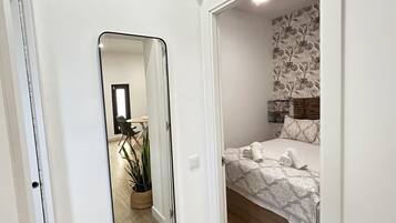 A bedroom with a bed, a mirror, and a view of a dining area.