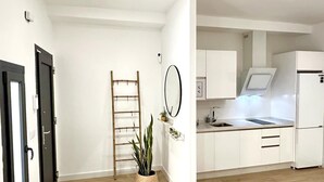 Ett modernt kök med vita skåp, en diskho i rostfritt stål och en inbyggd ugn. En trästege står lutad mot väggen och en krukväxt står på golvet.