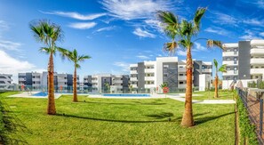 A modern residential complex with multiple apartment buildings, a swimming pool, and palm trees. - Carma | pool- sea view - terrace (Fuengirola)