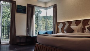 Een moderne hotelkamer met een groot bed, een zithoek bij het raam en uitzicht op de omgeving.