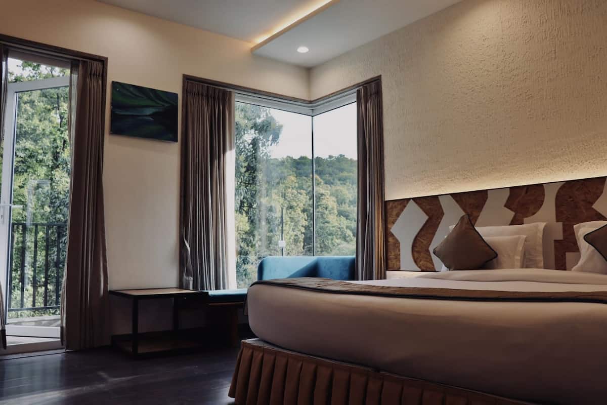 Een moderne hotelkamer met een groot bed, een zithoek bij het raam en uitzicht op de omgeving.