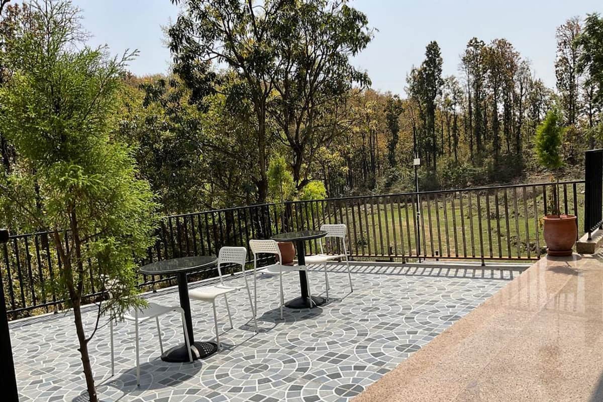 Een terras buiten met betegelde vloer, een metalen hekwerk en zitplaatsen.