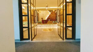 Een hotellobby met een receptiebalie, een zithoek en een trap naar de verdiepingen erboven.