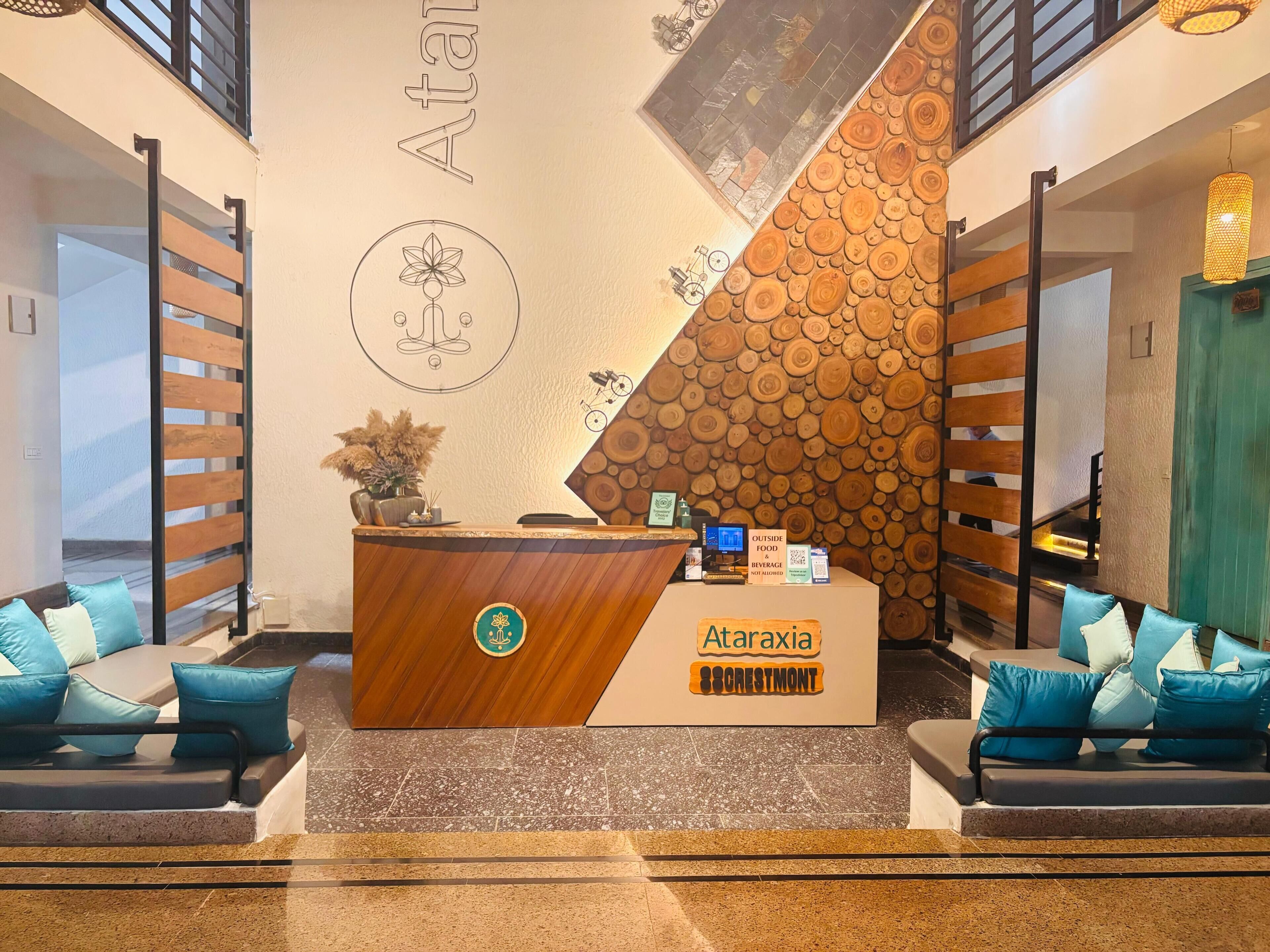 A reception area with a wooden reception desk, a sign for 'Ataraxia Crestmont', and a wall with a circular design and a wooden log pattern.