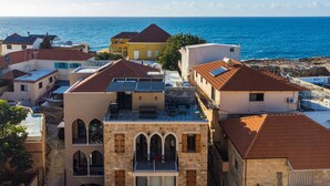 A coastal town with buildings featuring red-tiled roofs and a prominent building with a balcony overlooking the sea. - Bubble Beach 2-BR in Souk Batroun with Parking
 (Batroun)