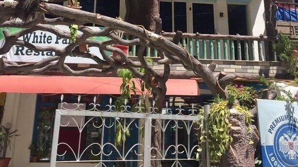Un immeuble sur lequel on peut lire l’inscription : « White Palace Hotel, suites avec balcon ».