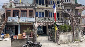 Un immeuble à plusieurs étages doté d’un balcon, d’une enseigne indiquant qu’il s’agit d’un hôtel, et d’une moto garée devant.