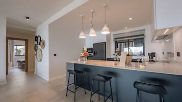 A modern kitchen with a large island, bar stools, pendant lights, and a view to the dining area.