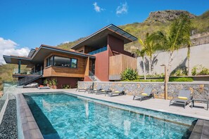 A modern house with a swimming pool, a wooden deck, and a stone wall. - Legend Hill Residences & Spa (Black River)