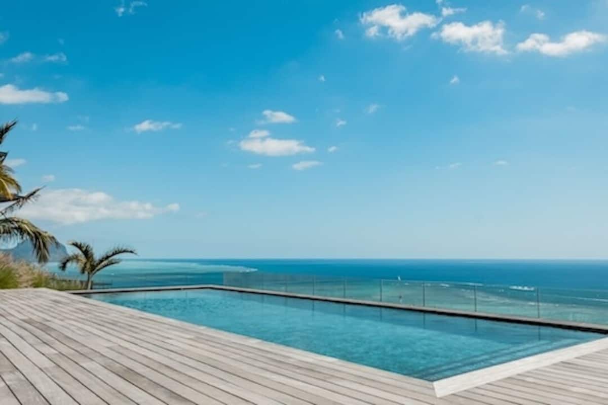 A wooden deck with a pool overlooking the ocean.