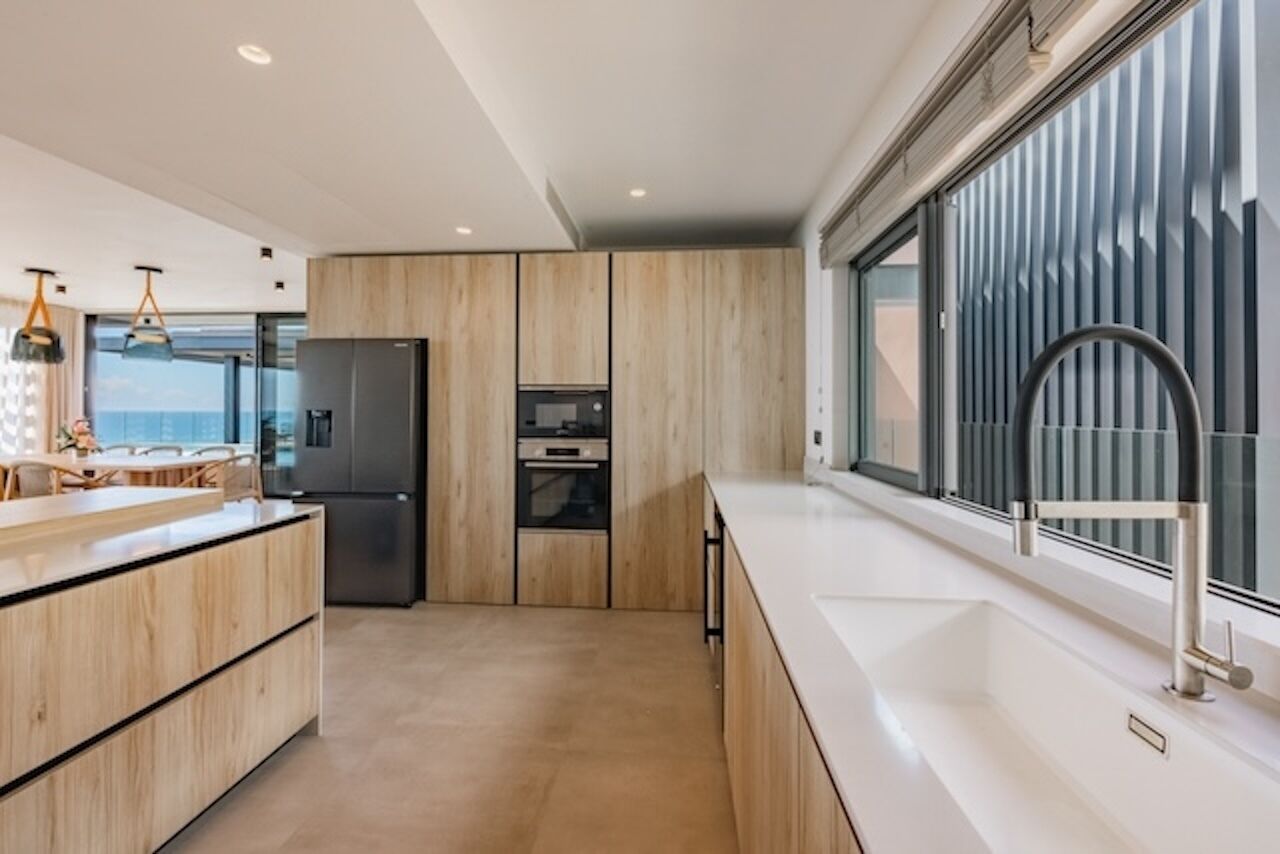 A modern kitchen with a large island, built-in oven, and a sleek stainless steel refrigerator.