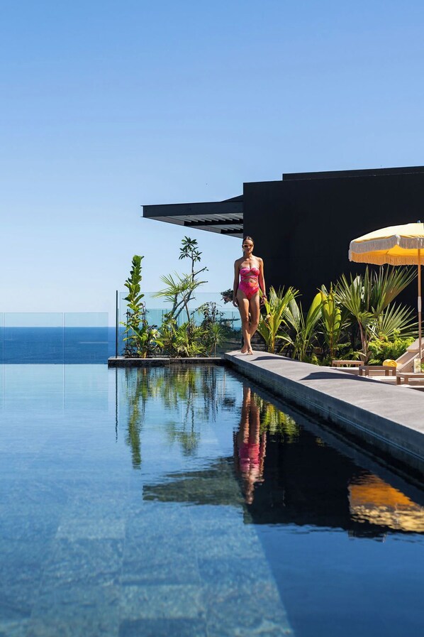A person standing at the edge of a clear pool with a view of the ocean. - Legend Hill Residences & Spa (Black River)