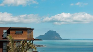 A modern building with a wooden facade and large windows, overlooking a calm sea and a prominent mountain in the distance. - Legend Hill Residences & Spa (Black River)