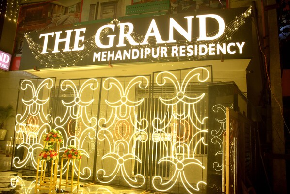 Residencia Grand Mehandipur con señalización iluminada y arreglos florales decorativos.
