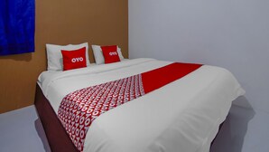 Ein Hotelzimmer mit einem Bett, zwei Kissen mit dem Logo "OYO" und einer roten und weißen Bettdecke.