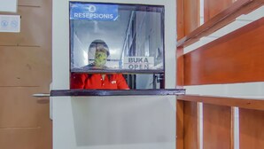 Ein Empfangsbereich mit einem Schild, auf dem 'RECEPTIONIS' und 'BUKA OPEN' steht.