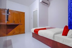 A bedroom with a bed, wooden wardrobe, and an air conditioning unit. - OYO 89994 Kartini House (Jakarta)