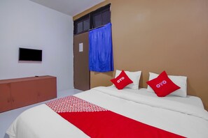 A hotel room with a bed, a TV, a wardrobe, and a window with a blue curtain. - OYO 89994 Kartini House (Jakarta)