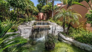A small waterfall in a lush garden with dense foliage and a stone wall. - Villa Federer: Best holiday rental in Marbella Old town (Marbella)