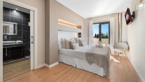Een moderne slaapkamer met een groot bed, een badkamer met spiegel en wastafel, en een balkon met uitzicht.