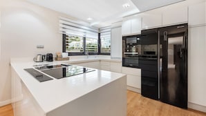 Een moderne keuken met een centraal eiland, ingebouwde apparatuur en uitzicht door het raam.