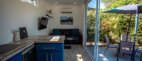 A modern kitchen with a built-in dishwasher, a blue cabinet, and a dining area with a table and chairs.