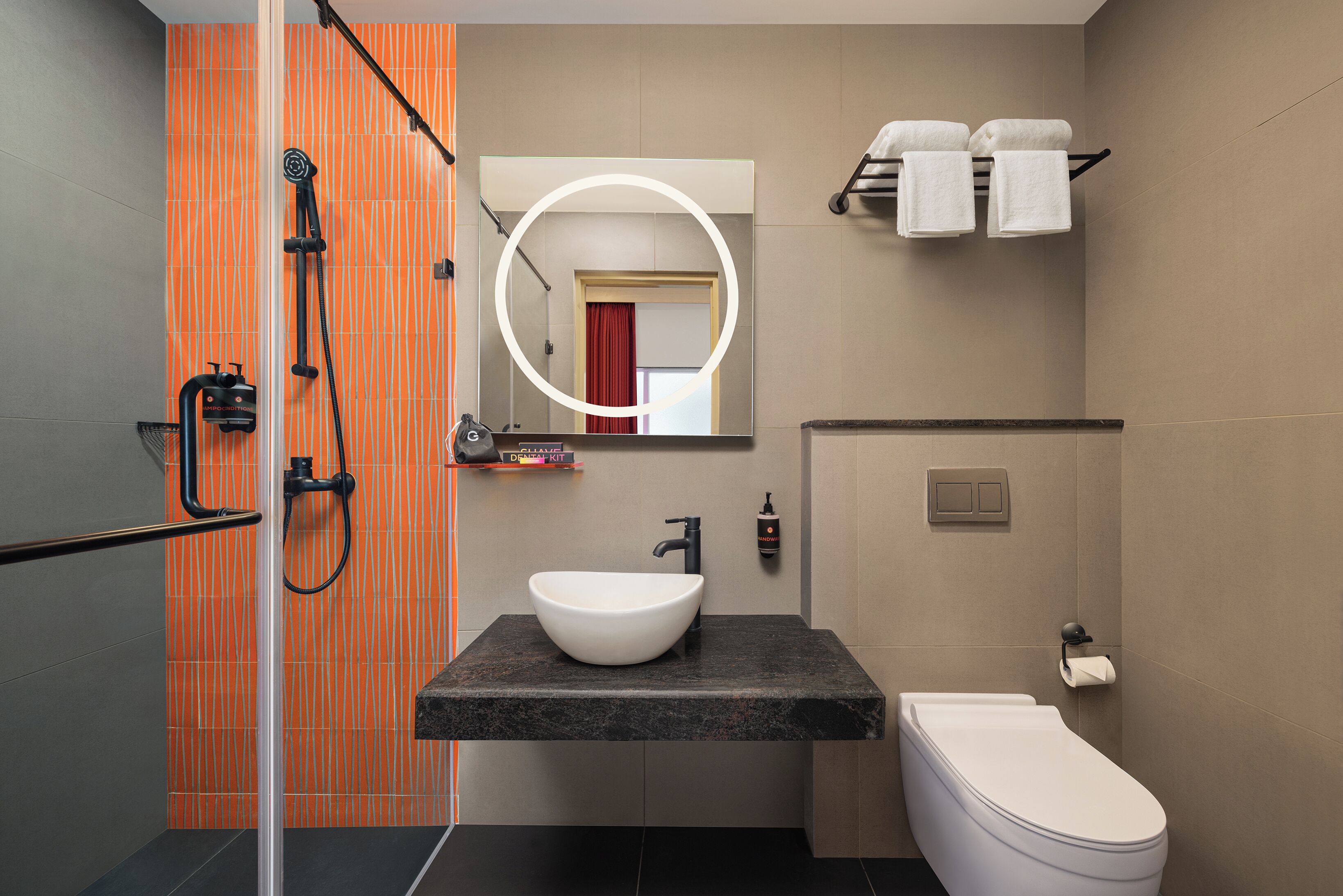Un baño moderno con cabina de ducha de vidrio, lavamanos blanco y un inodoro.