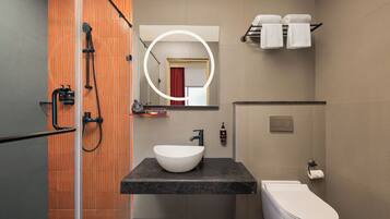 Un baño moderno con cabina de ducha de vidrio, lavamanos blanco y un inodoro.