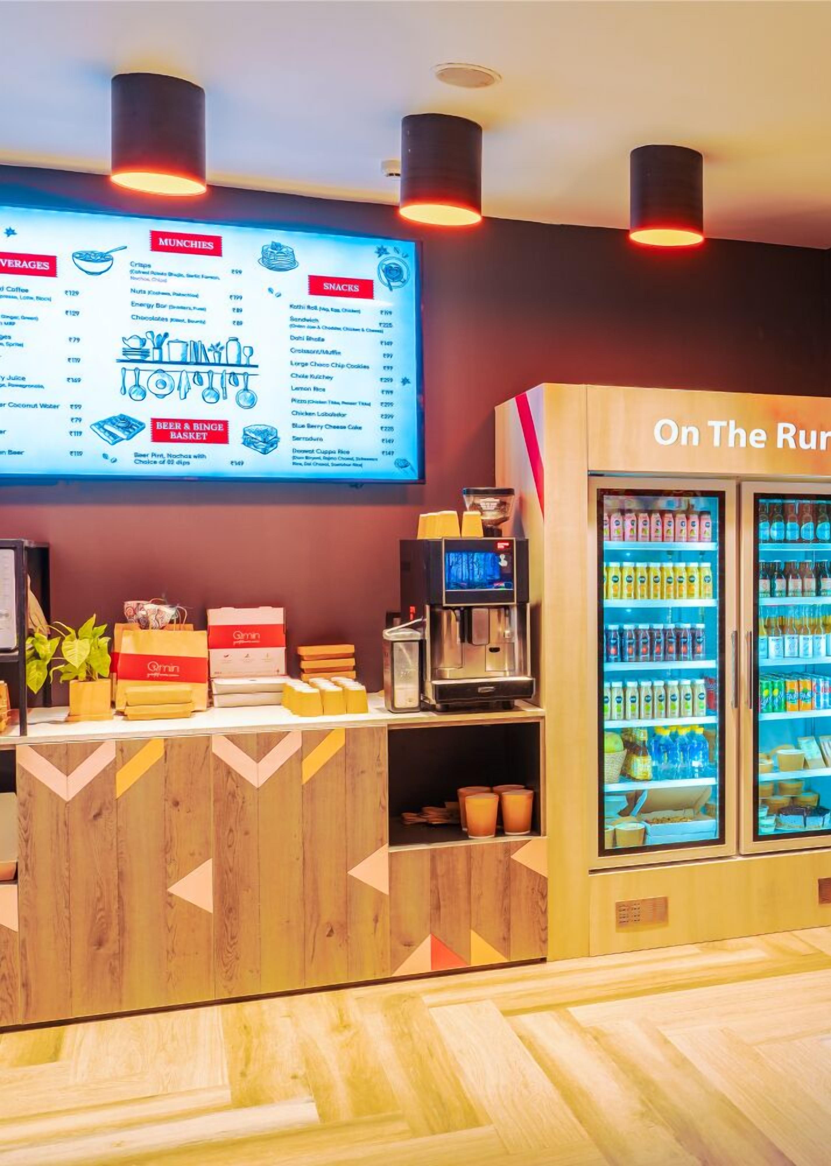 Un restaurante con un cartel de menú, una máquina de café y un refrigerador para bebidas.