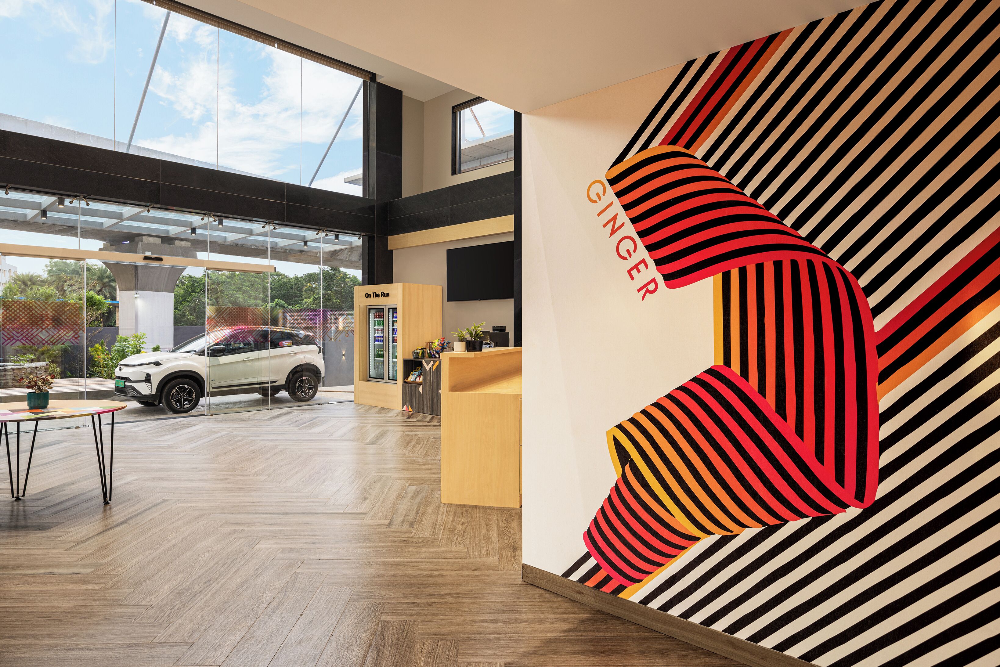 A modern interior with a large window, a white car, and a wall with a striped pattern and the word "GINGER".