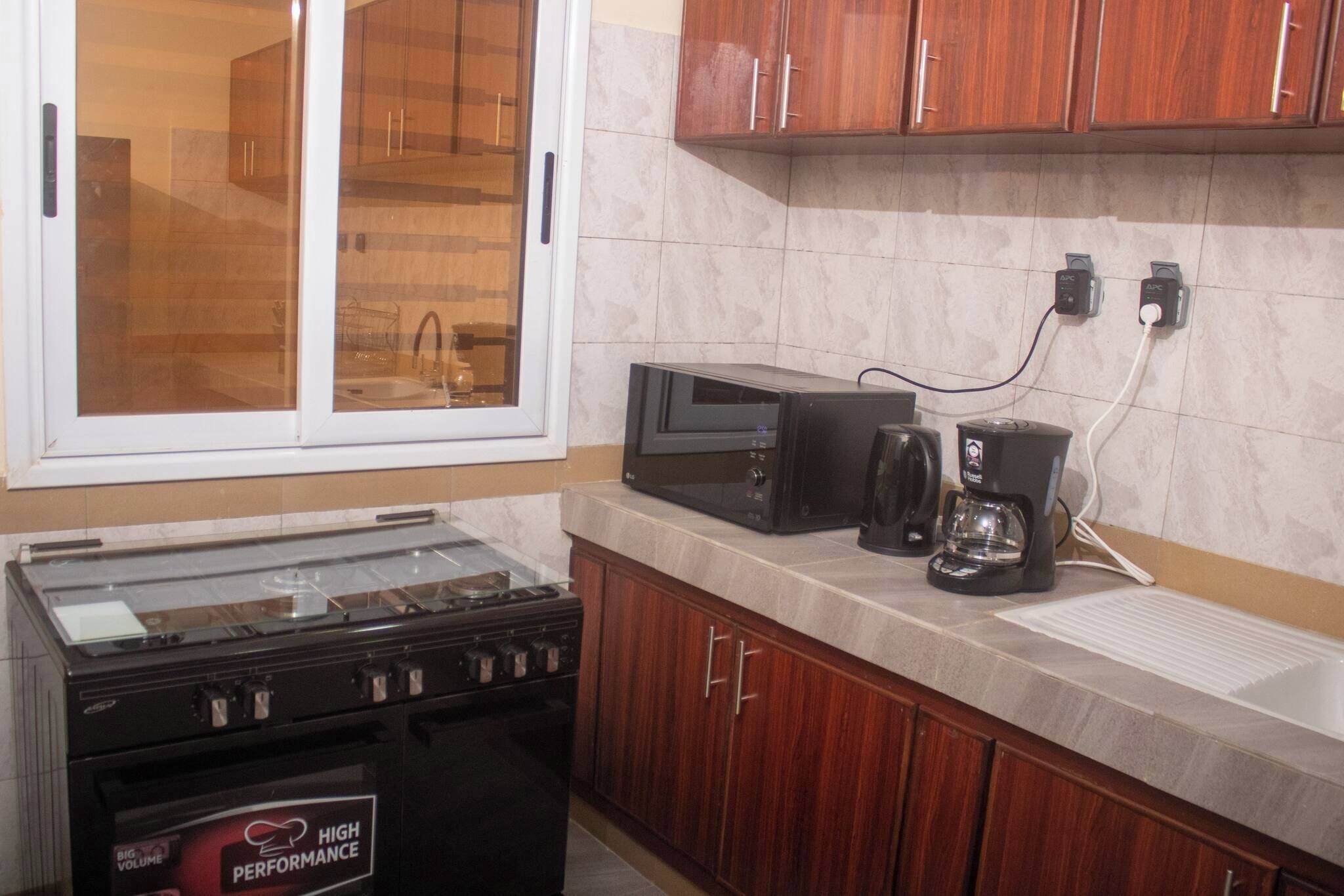 A kitchen with a stove, microwave, coffee maker, and wooden cabinets.