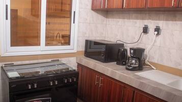 A kitchen with a stove, microwave, coffee maker, and wooden cabinets.