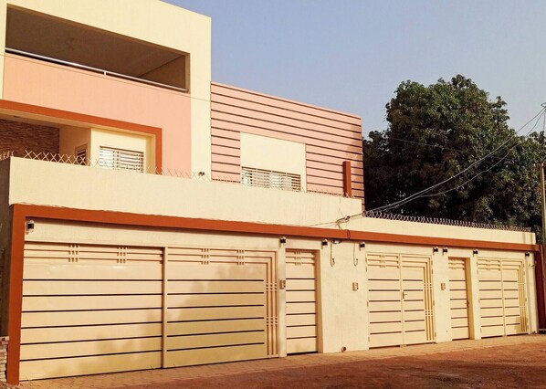 A modern two-story building with a flat roof, a balcony, and a row of garage doors.
