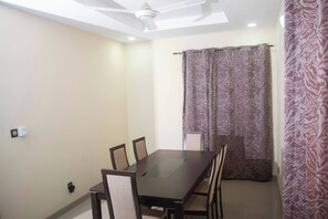 A dining area with a table and chairs, a ceiling fan, and patterned curtains.