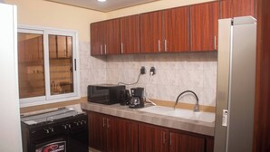 Una cocina con armarios de madera, microondas, cafetera, lavaplatos y refrigerador.