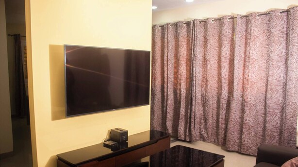 Una sala de estar con televisor de pantalla plana montado en la pared, una mesa de centro y un sofá.