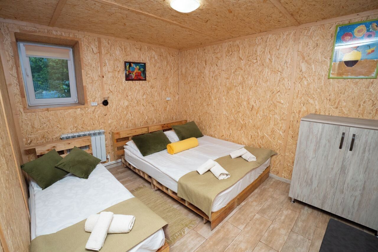 Una habitación con dos camas de madera, un armario y una ventana que da a zonas verdes.