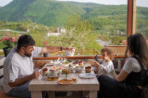 Una mesa de comedor con comida y bebidas, con un hermoso paisaje de montañas al fondo.