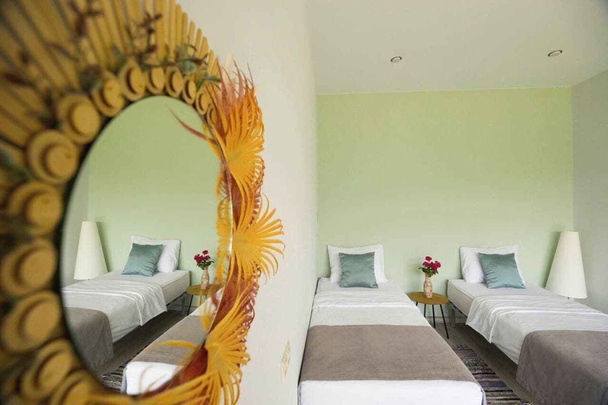 A hotel room with two beds, a large mirror, and a decorative wall piece.