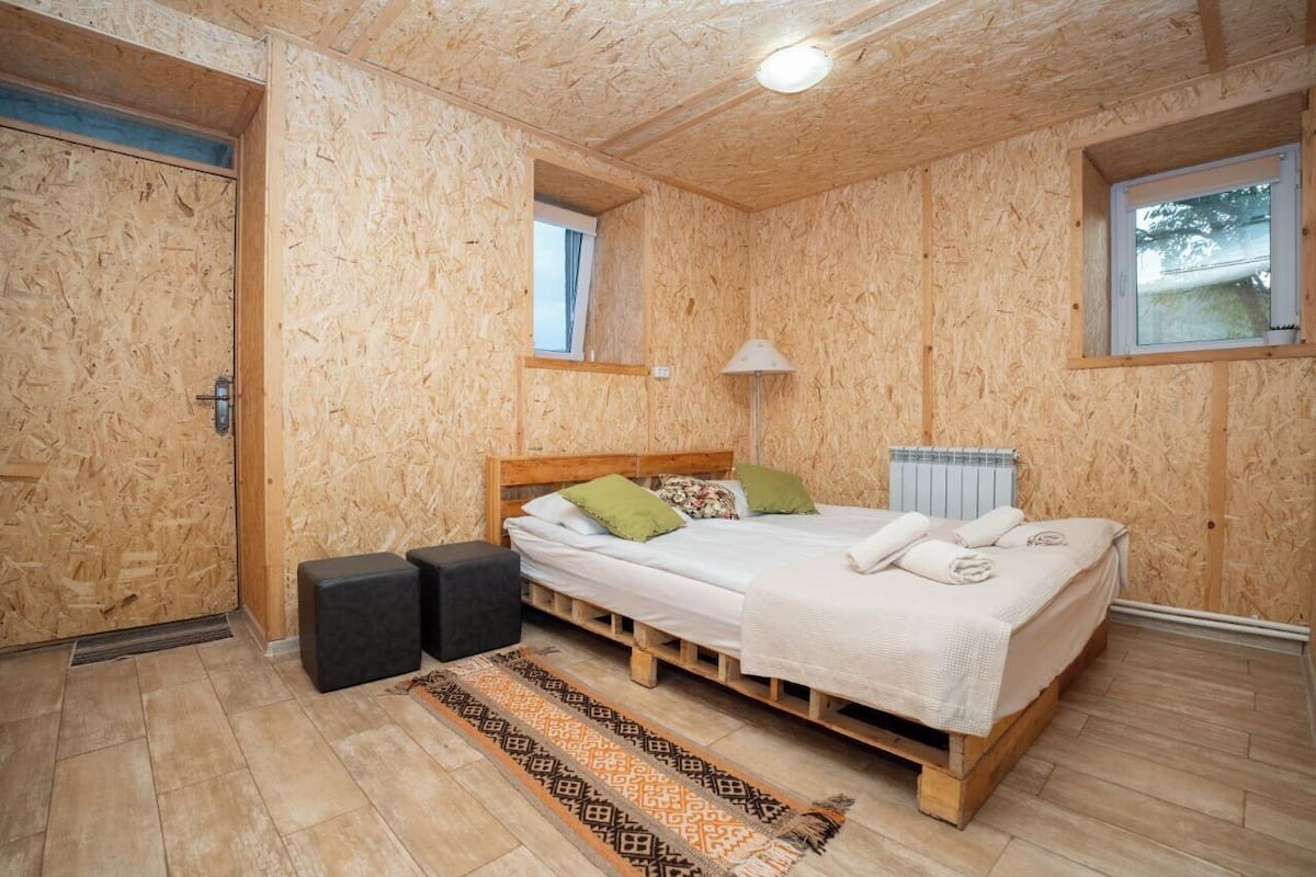 A bedroom with a wooden bunk bed, a small window, a radiator, and a patterned rug.