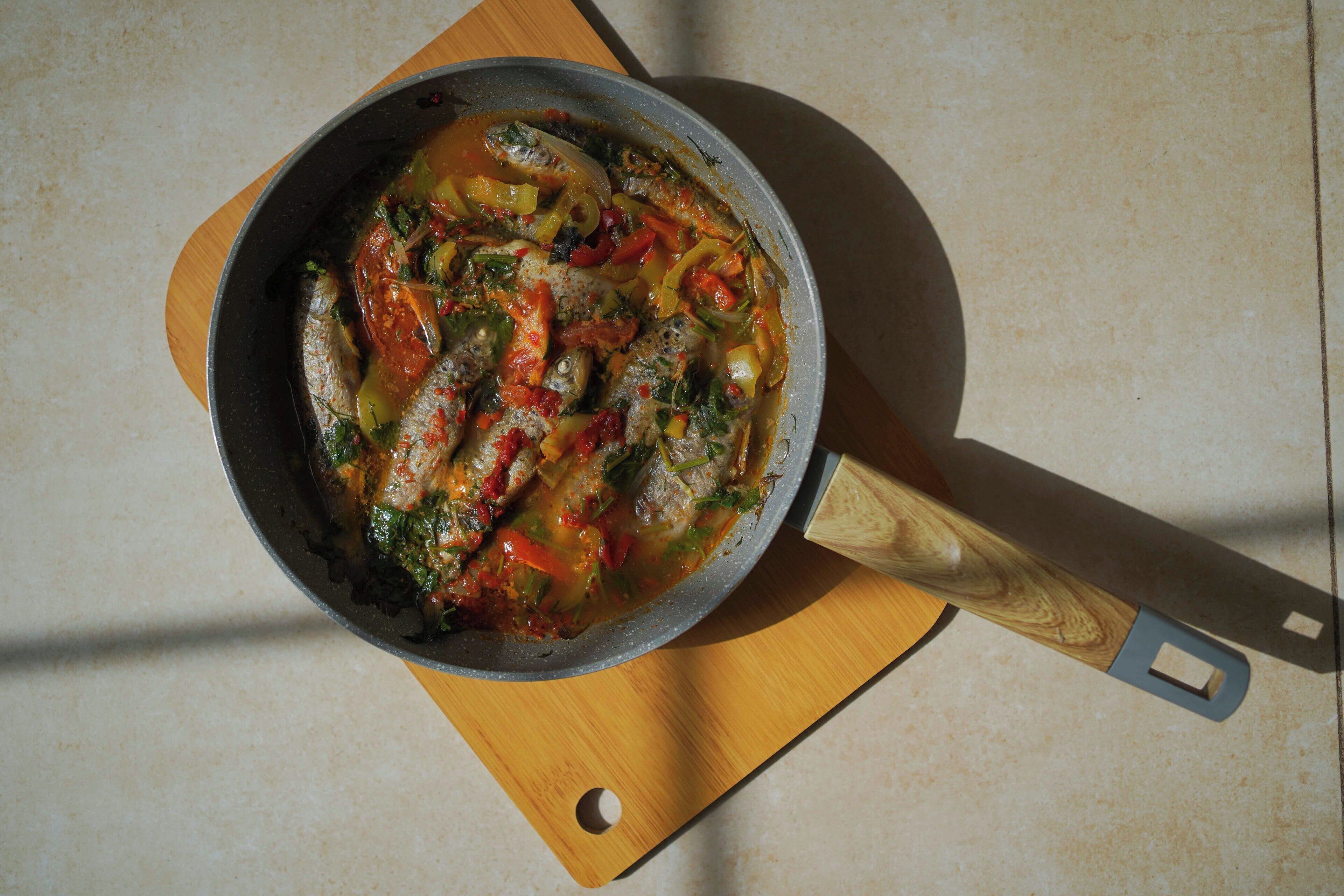 Un plat de ragoût de poisson aux légumes, servi sur une planche en bois.